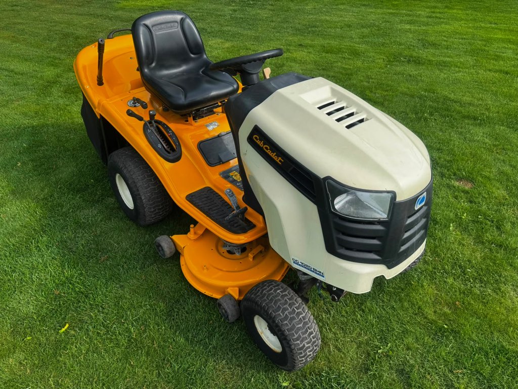 Biało-pomarańczowy traktorek ogrodowy Cub Cadet na trawniku